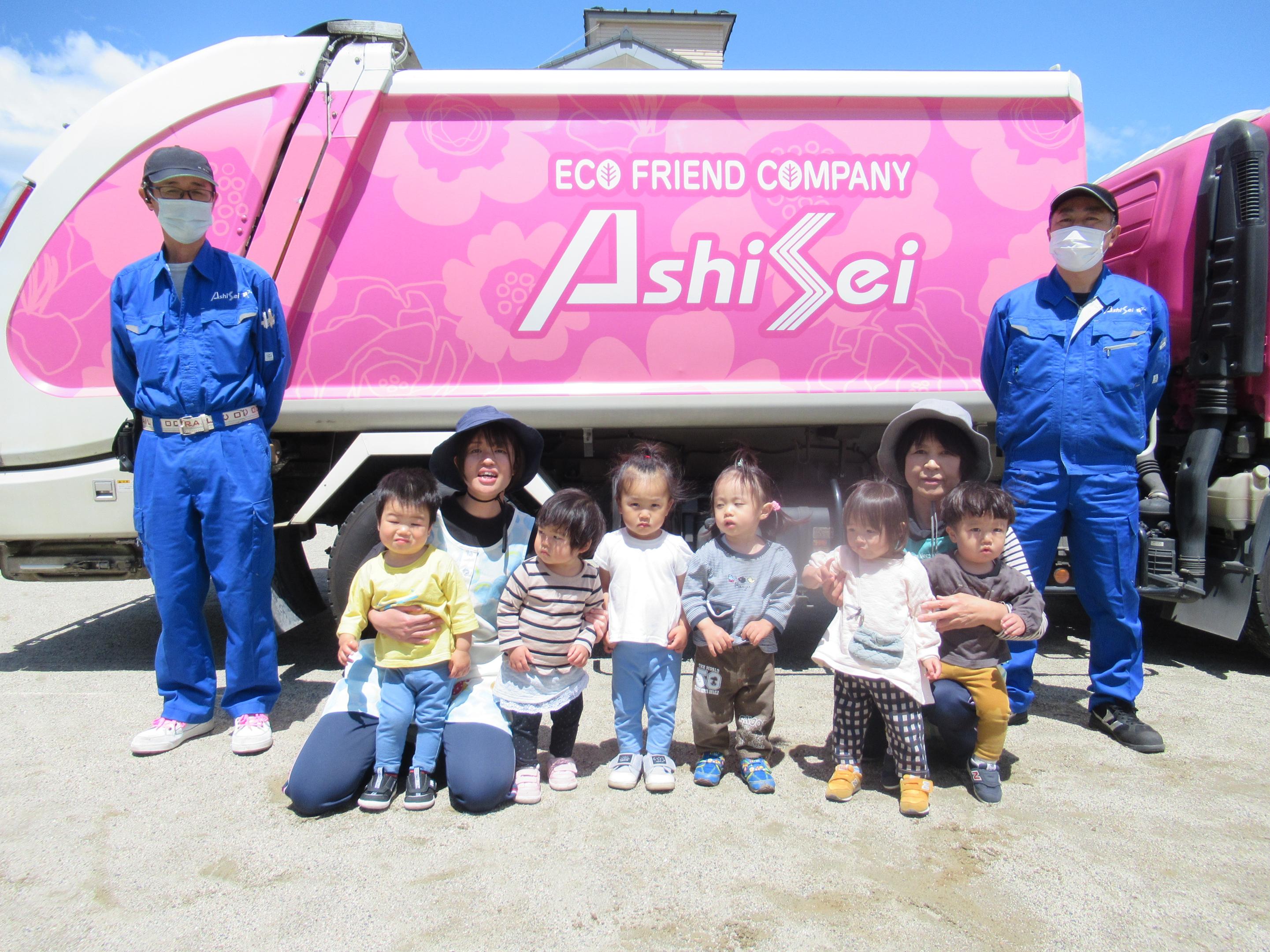 子どもがゴミ収集車の前にいる写真
