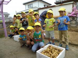 5歳児が収穫したジャガイモを持ち、記念撮影をしているところです。