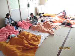  2歳児、3歳児が保育者に体をさすってもらいながら、畳の部屋でお昼寝をしているところです。して