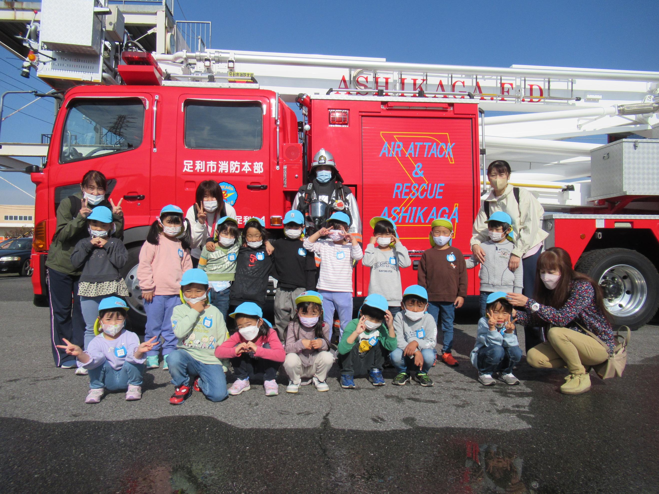 子どもが消防車の前にいる写真